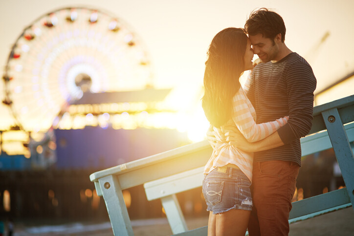 photo of a romantic couple embracing at sunset in front of santa monica ferris wheel.