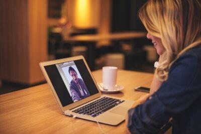 Pretty woman is having a voice call over computer with her boyfriend.