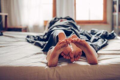 Adult couple's feet looking out of bed after one-night stand