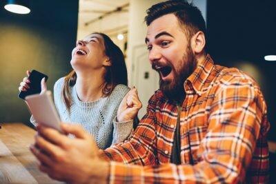 Excited male and female hipsters rejoice in winning an internet lottery made bets on website on modern smartphone.Happy couple in love celebrating victory in online competitions enjoying success
