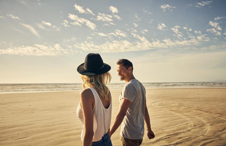 A couple walking on a beach and holding hands