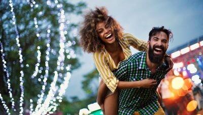 Young couple enjoying at music festival. They are laughing and looking at camera, relationship