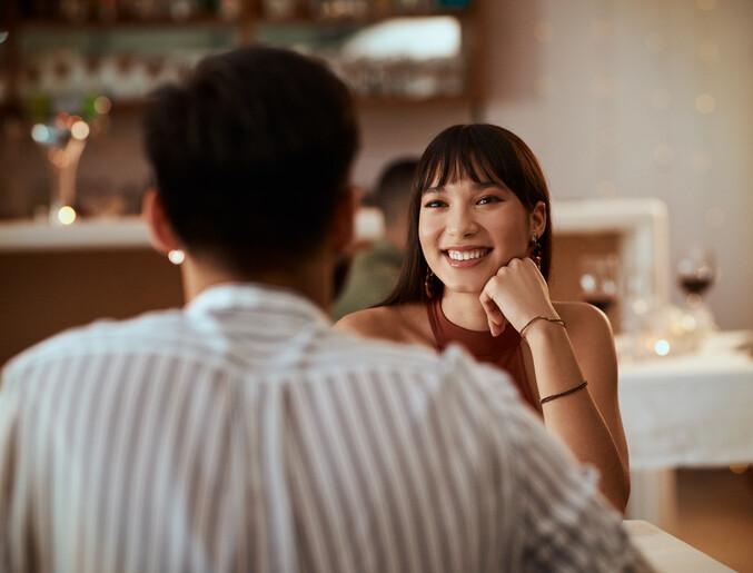 young woman smiling while on a date at a restaurant, flirting