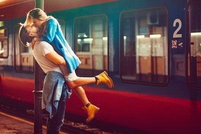 Passionate young man and woman kissing beside the train at the railway station. The shot is executed with available natural light, and the copy space has been left.