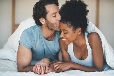 Shot of an affectionate middle aged man kissing his wife on her forehead while relaxing on their bed at home. get relationship-confident