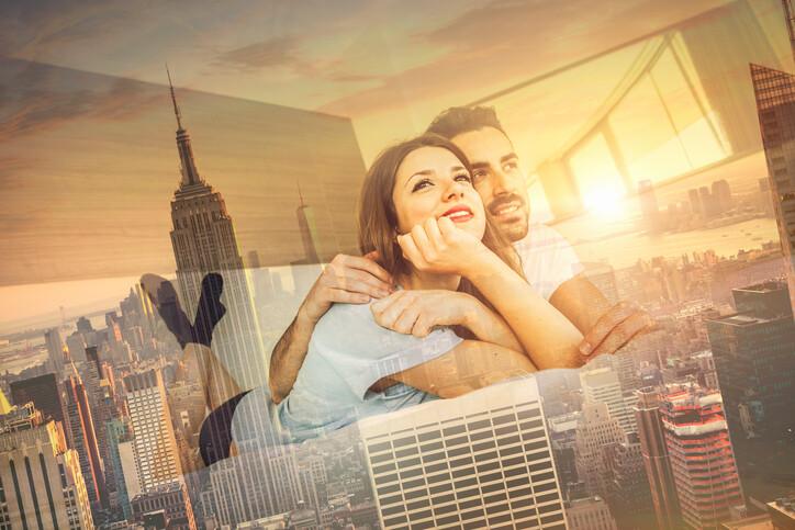 couple looking out a window with a reflection of the Empire State building