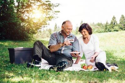 Elderly couple having picnic on the mountain meadow near forest after divorce
