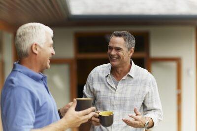 Happy male friends having coffee at yard maintaining friend relationship