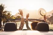a couple in a car, the couple holding their hands up in a convertible car.