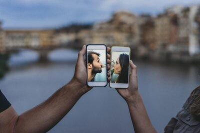 Conceptual shot of a young adult couple kissing via mobile phone on dating apps