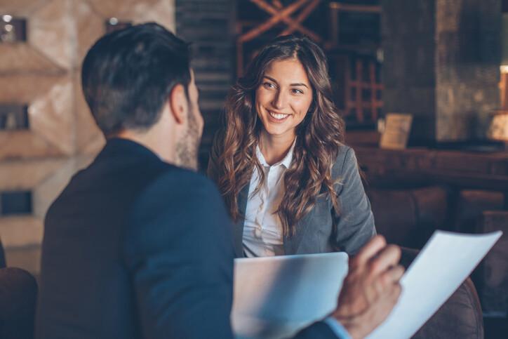 Two people in formal businesswear talking and smiling