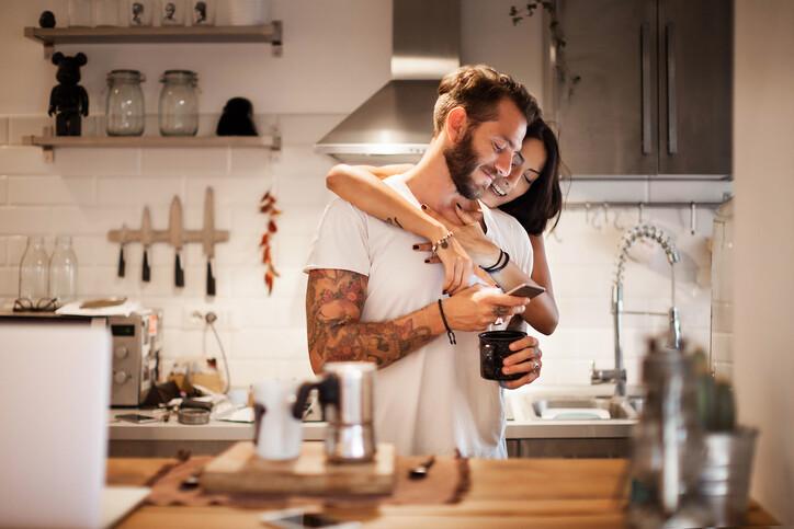 Young couple at home using smartphone - Morning breakfast time