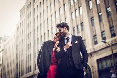 professional dressed couple in love walking down the street early in spring.